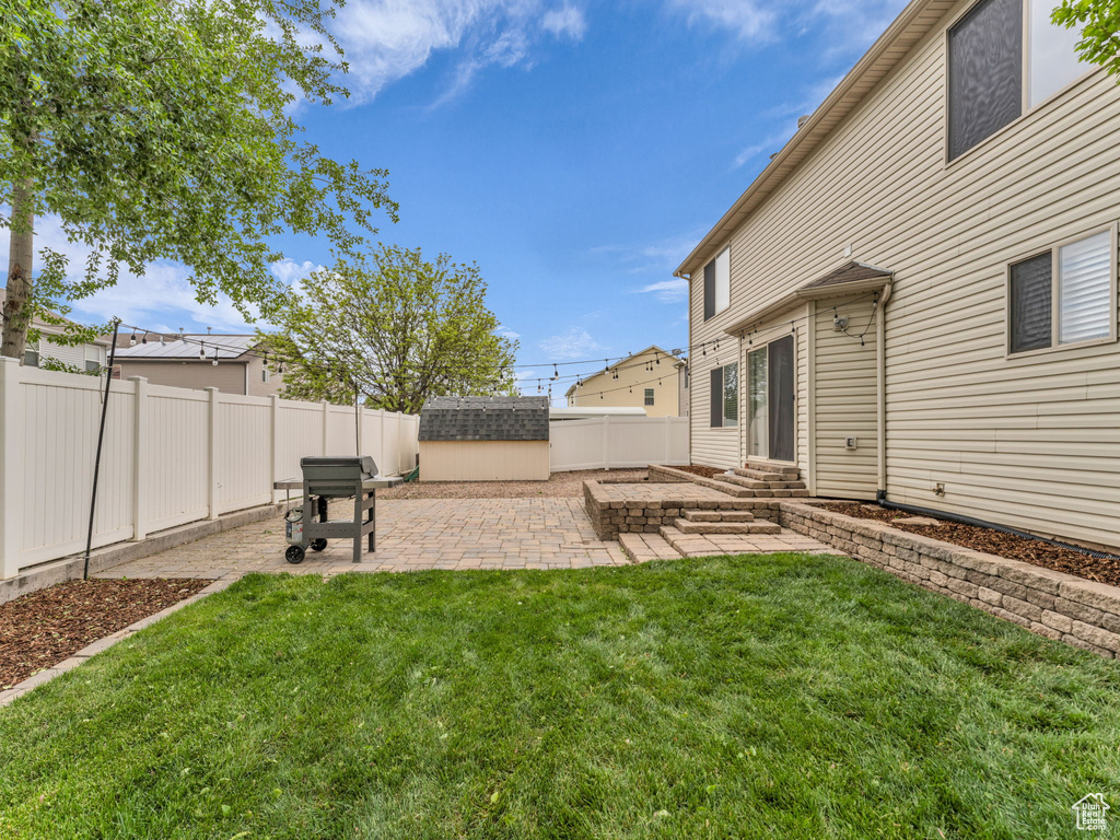 View of yard featuring an outdoor structure, a storage unit, a patio, a fenced backyard, and entry steps