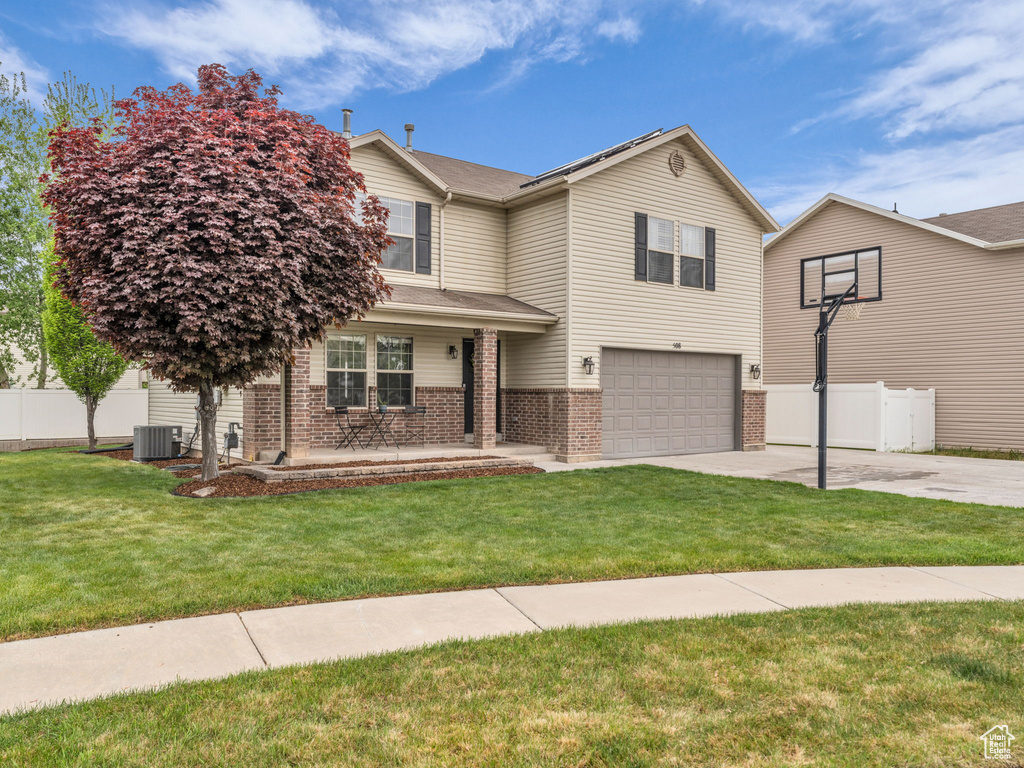 Traditional home featuring brick siding, fence, a garage, central AC, and concrete driveway