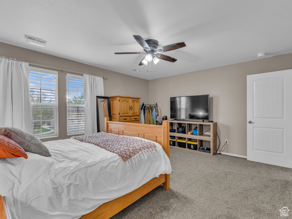 Bedroom with baseboards, ceiling fan, carpet flooring, and visible vents