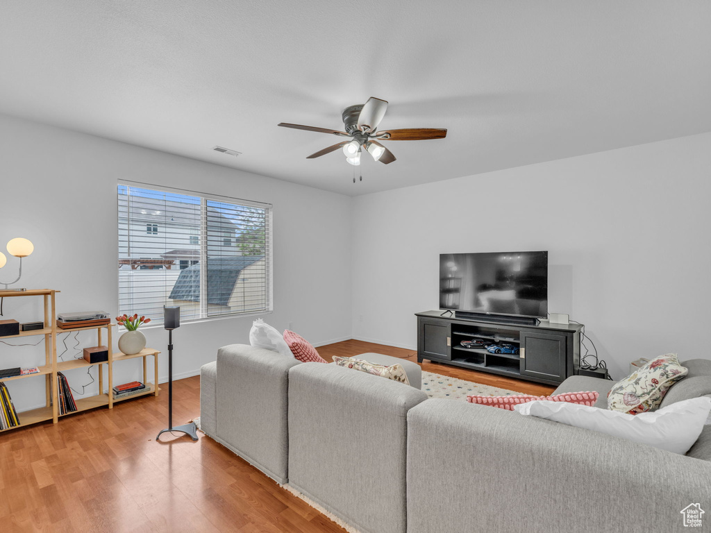 Living area featuring baseboards, visible vents, ceiling fan, and wood finished floors