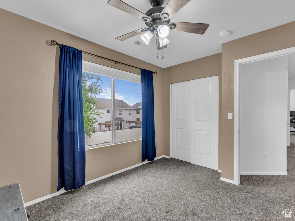 Unfurnished bedroom featuring carpet, a closet, visible vents, baseboards, and ceiling fan