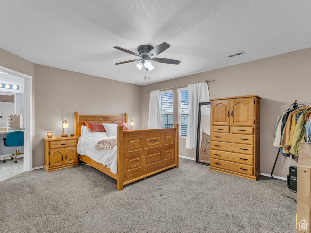 Bedroom with a ceiling fan, baseboards, ensuite bath, visible vents, and light carpet