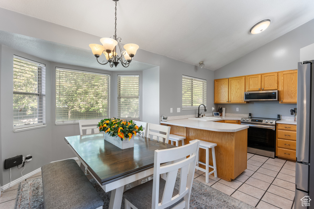 Kitchen featuring stainless steel appliances, lofted ceiling, a sink, light countertops, and a peninsula