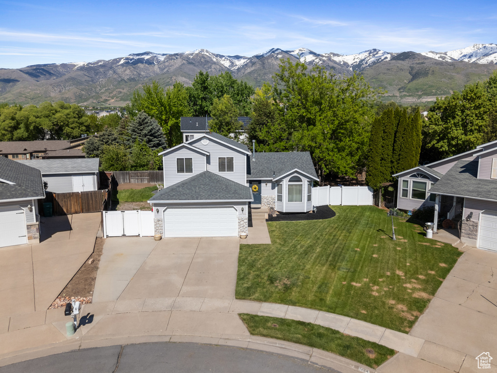 View of front facade with concrete driveway, a garage, a mountain view, stone siding, and a shingled roof