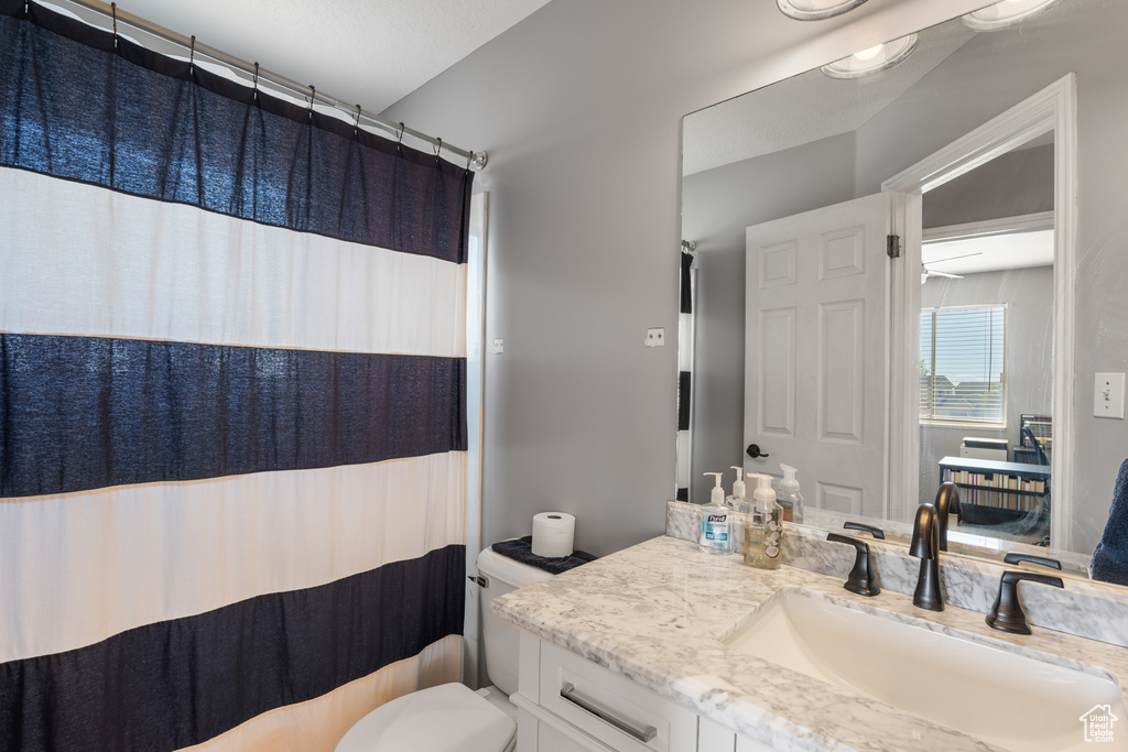 Bathroom with toilet, vanity, and curtained shower