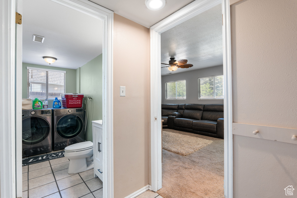 Bathroom featuring washing machine and dryer, a ceiling fan, tile patterned floors, and toilet