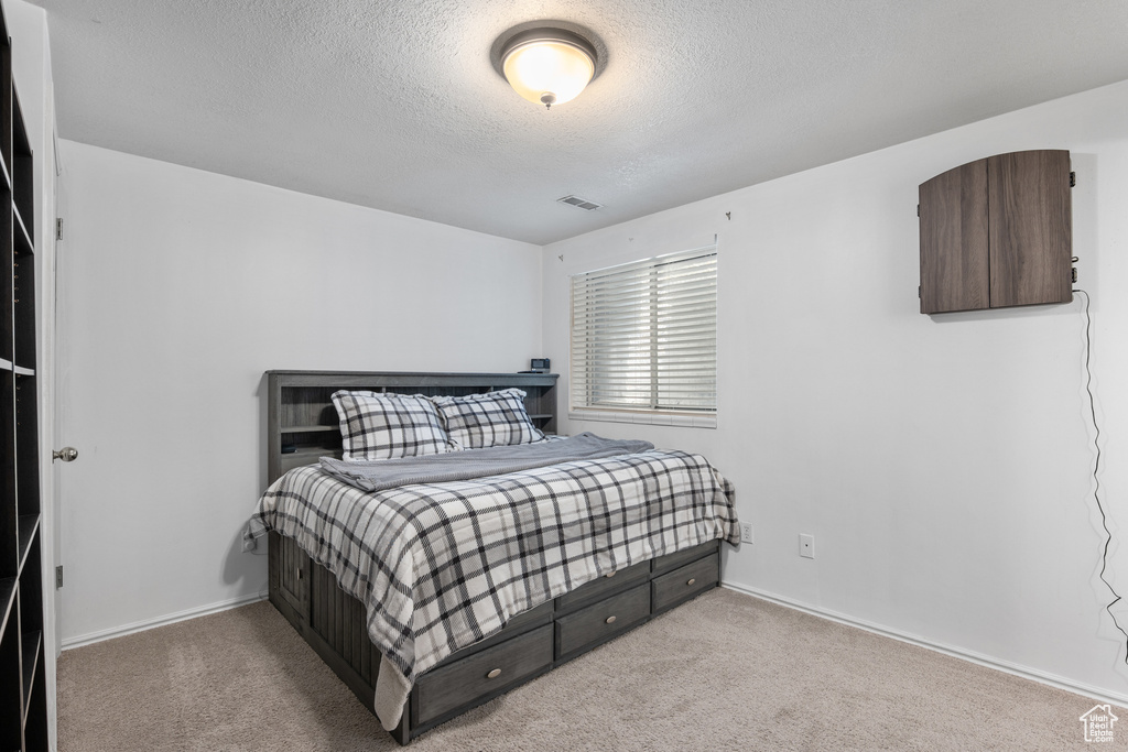 Bedroom featuring a textured ceiling, carpet, and baseboards