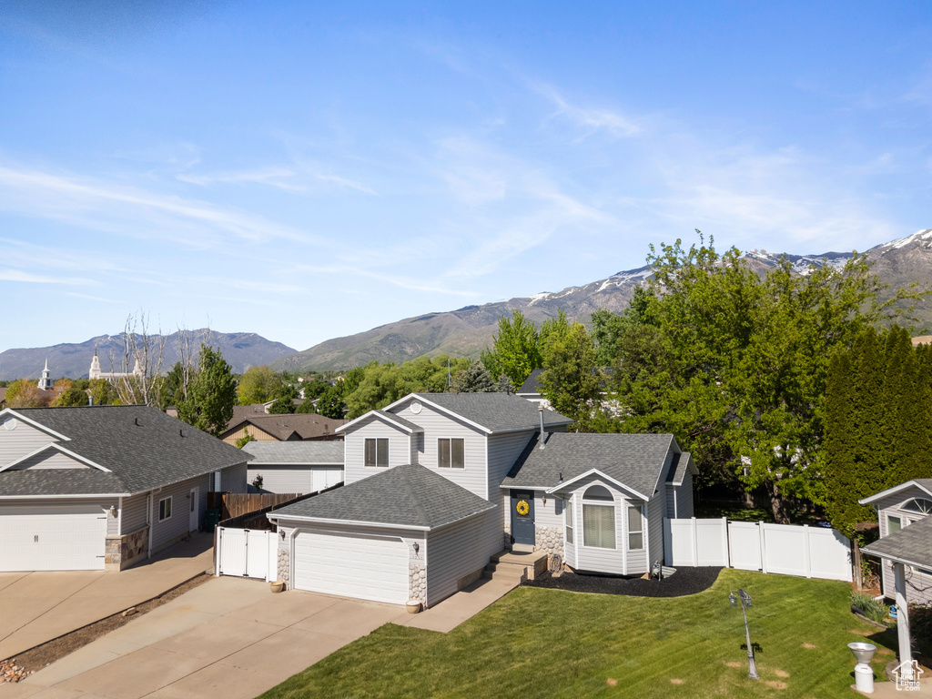 View of front of home featuring stone siding, driveway, a mountain view, and a garage