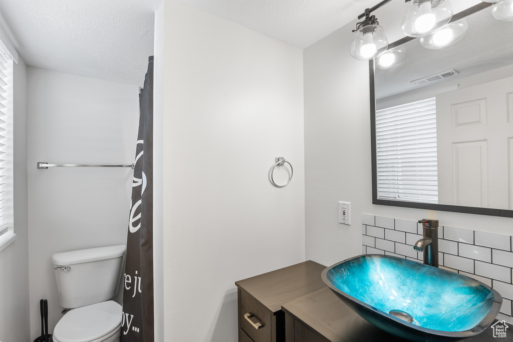 Bathroom featuring tasteful backsplash, toilet, vanity, and a textured ceiling