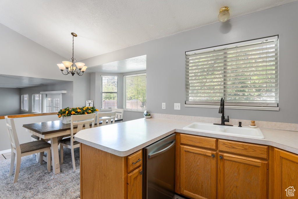 Kitchen featuring a sink, dishwasher, light countertops, a chandelier, and lofted ceiling