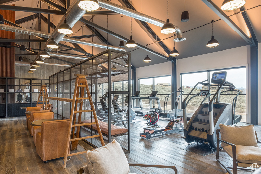 Workout area with high vaulted ceiling and hardwood / wood-style floors