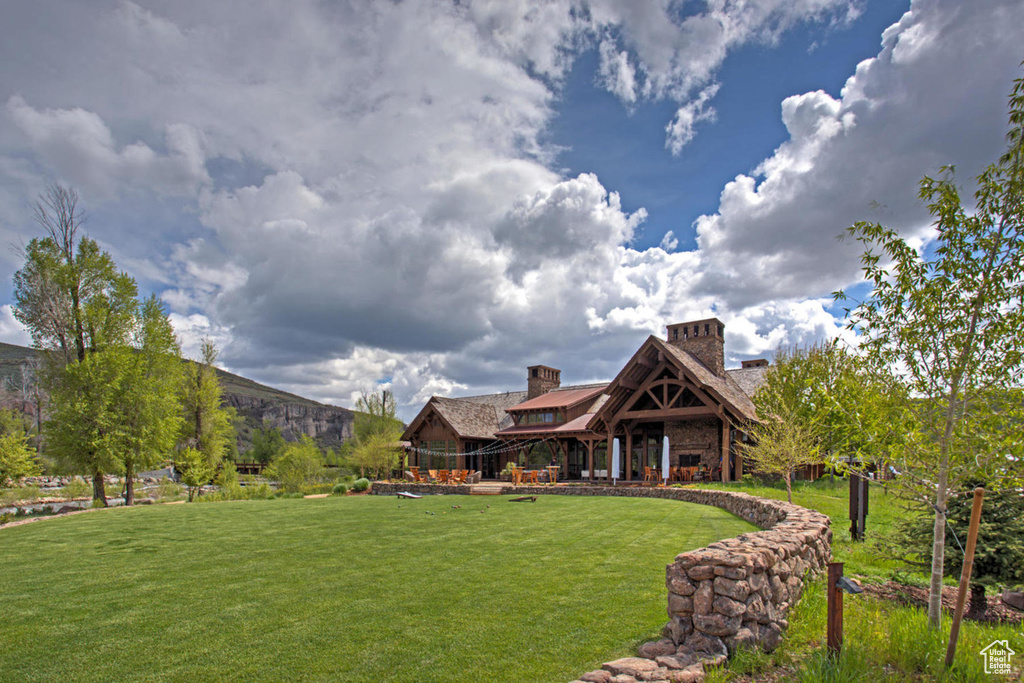 Rear view of property with a yard, a chimney, a gazebo, and stone siding