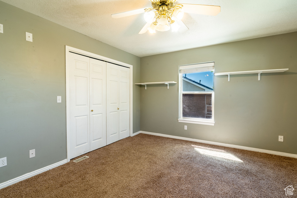 Unfurnished bedroom with carpet floors, a closet, baseboards, and ceiling fan