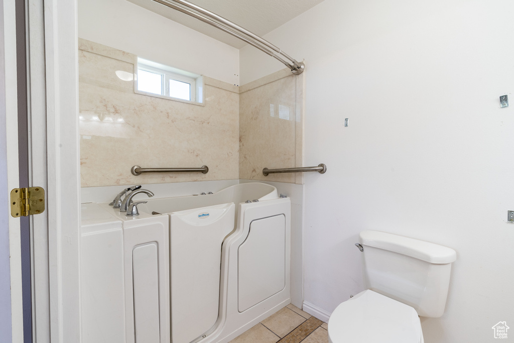 Full bathroom with tile patterned floors, toilet, and a bath