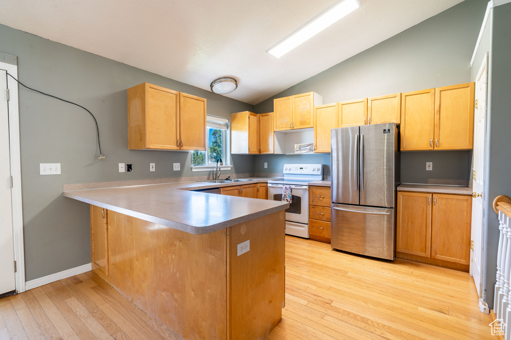 Kitchen featuring freestanding refrigerator, white electric stove, lofted ceiling, light wood-type flooring, and a peninsula