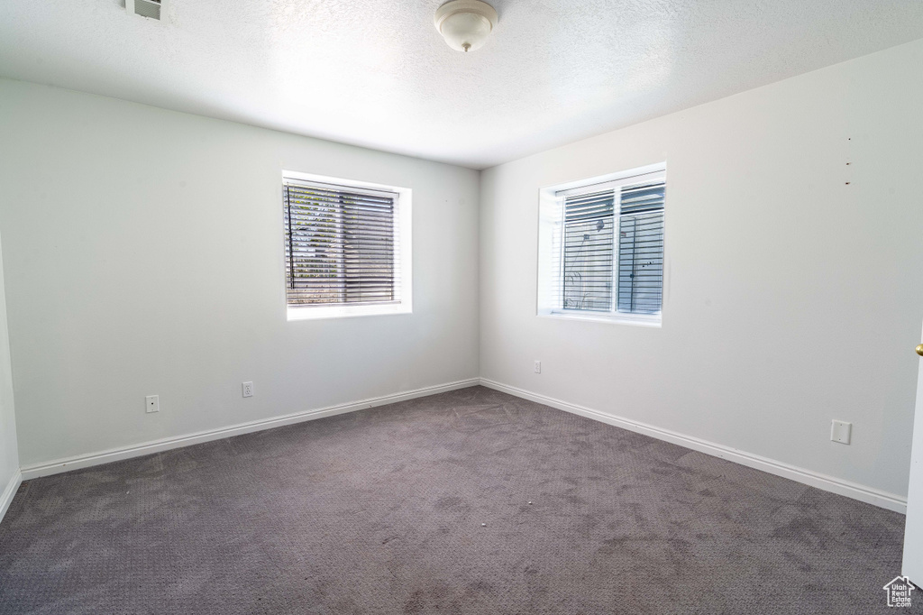Unfurnished room with dark colored carpet, baseboards, and a textured ceiling