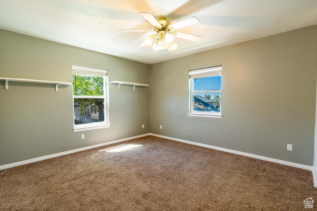 Spare room featuring carpet floors, ceiling fan, baseboards, and a textured ceiling