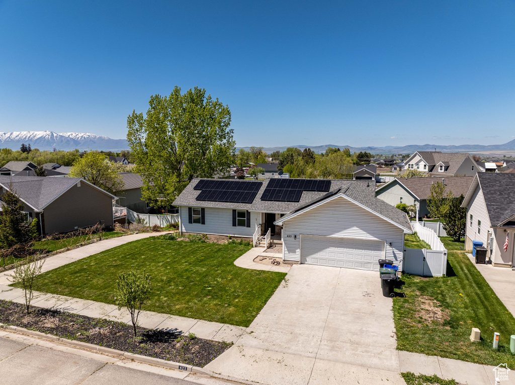 Ranch-style house featuring roof mounted solar panels, an attached garage, a residential view, and concrete driveway
