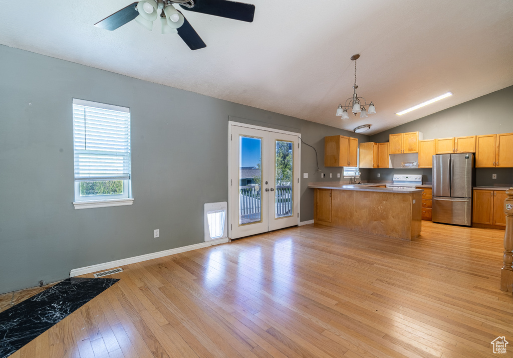 Kitchen with freestanding refrigerator, lofted ceiling, light wood-type flooring, a peninsula, and ceiling fan