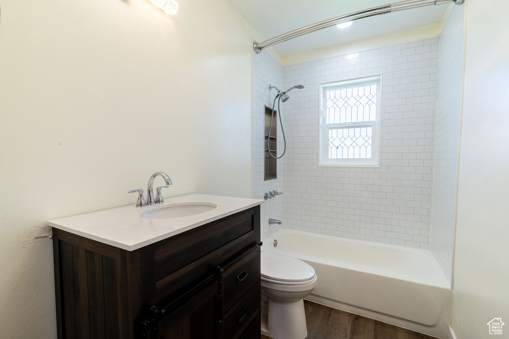 Bathroom with toilet, wood finished floors,  shower combination, and vanity