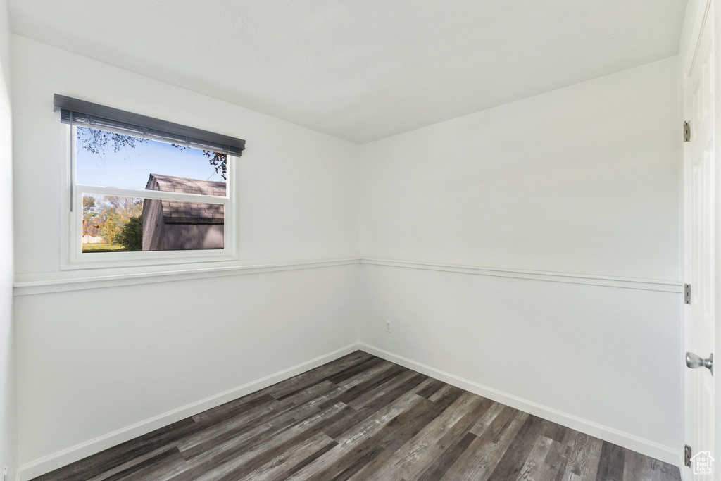 Unfurnished room featuring dark wood-style floors and baseboards