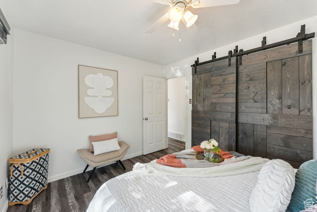 Bedroom featuring a barn door, wood finished floors, baseboards, and ceiling fan