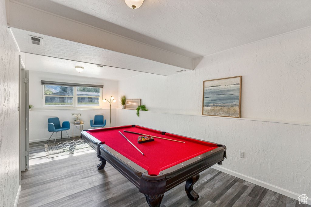 Recreation room featuring wood finished floors, pool table, baseboards, and a textured wall