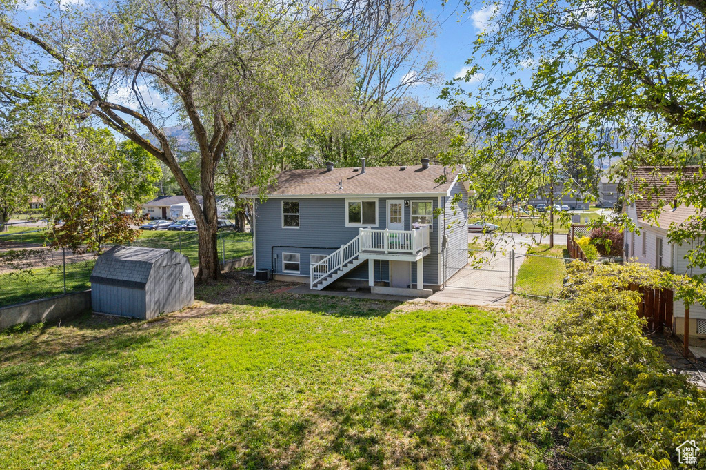 Back of house featuring stairway, a storage unit, an outdoor structure, a wooden deck, and a shingled roof