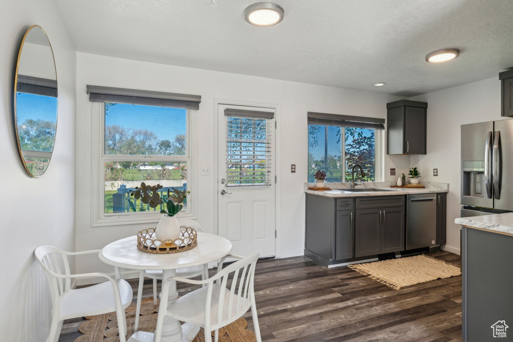 Kitchen with stainless steel appliances, a sink, light countertops, dark wood-type flooring, and a textured ceiling