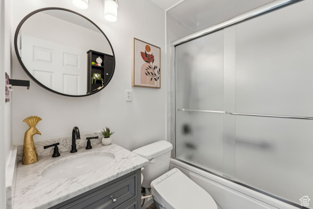Bathroom featuring vanity, toilet, and enclosed tub / shower combo
