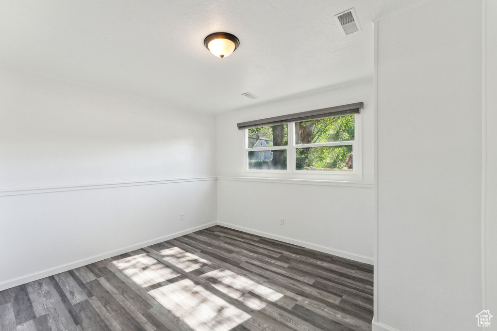 Spare room featuring dark wood-style floors and baseboards