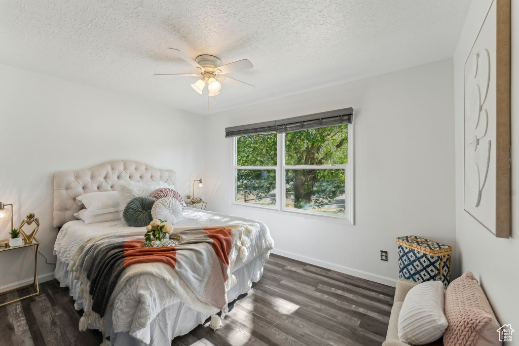 Bedroom with baseboards, dark wood-style flooring, a textured ceiling, and ceiling fan