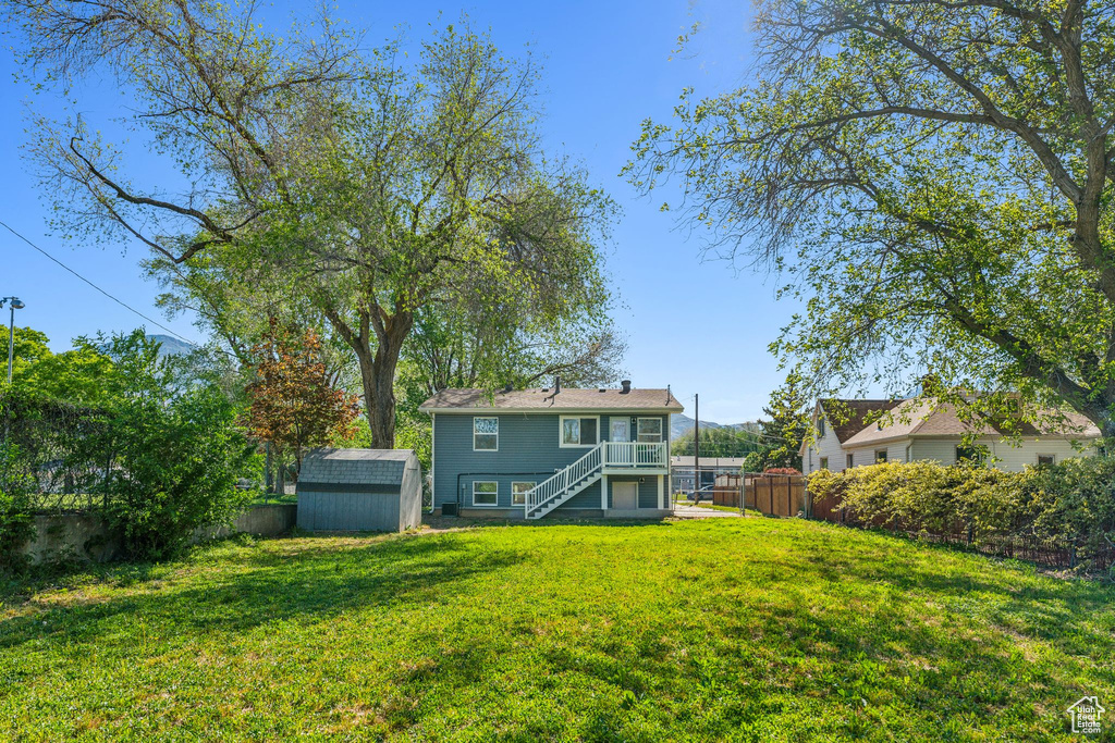 Back of property with stairway, a storage shed, an outbuilding, and a deck