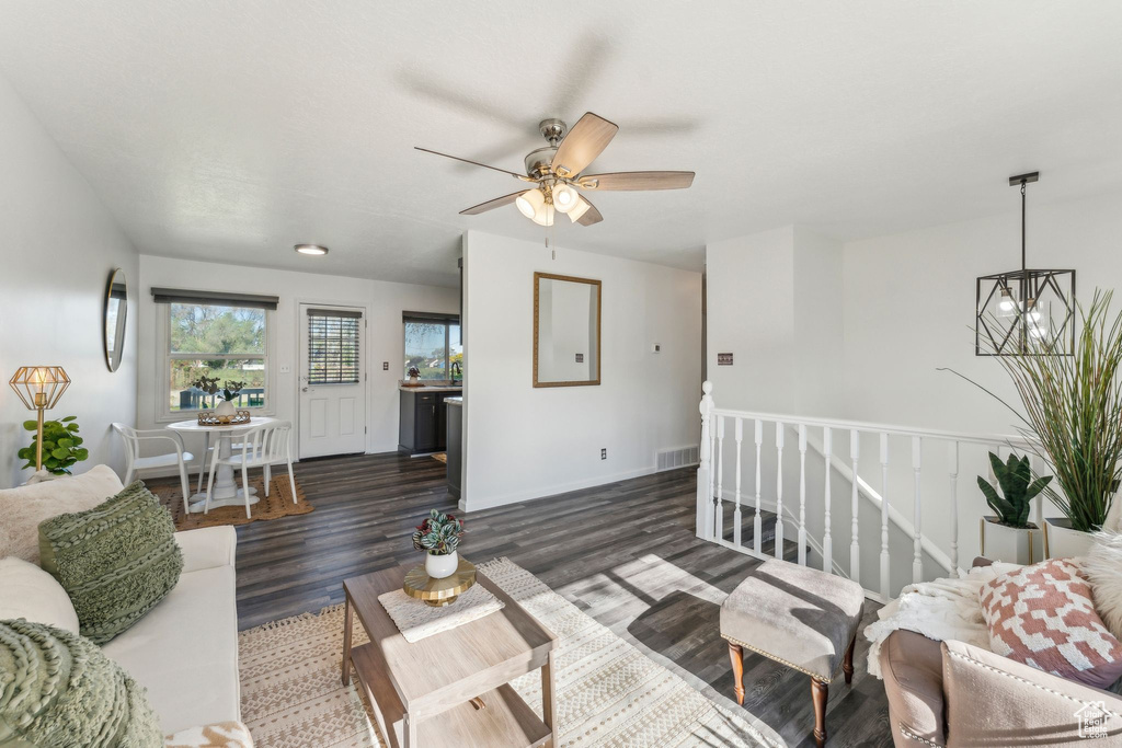 Living room featuring wood finished floors, a ceiling fan, a chandelier, and baseboards