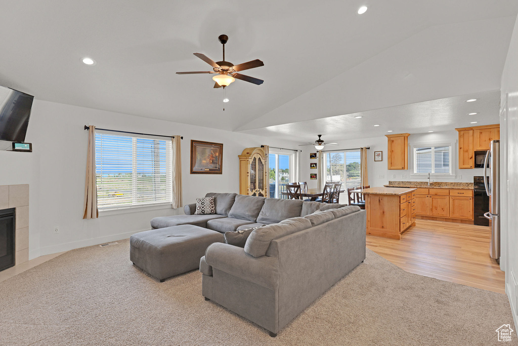 Living room with a ceiling fan, lofted ceiling, recessed lighting, a tile fireplace, and baseboards