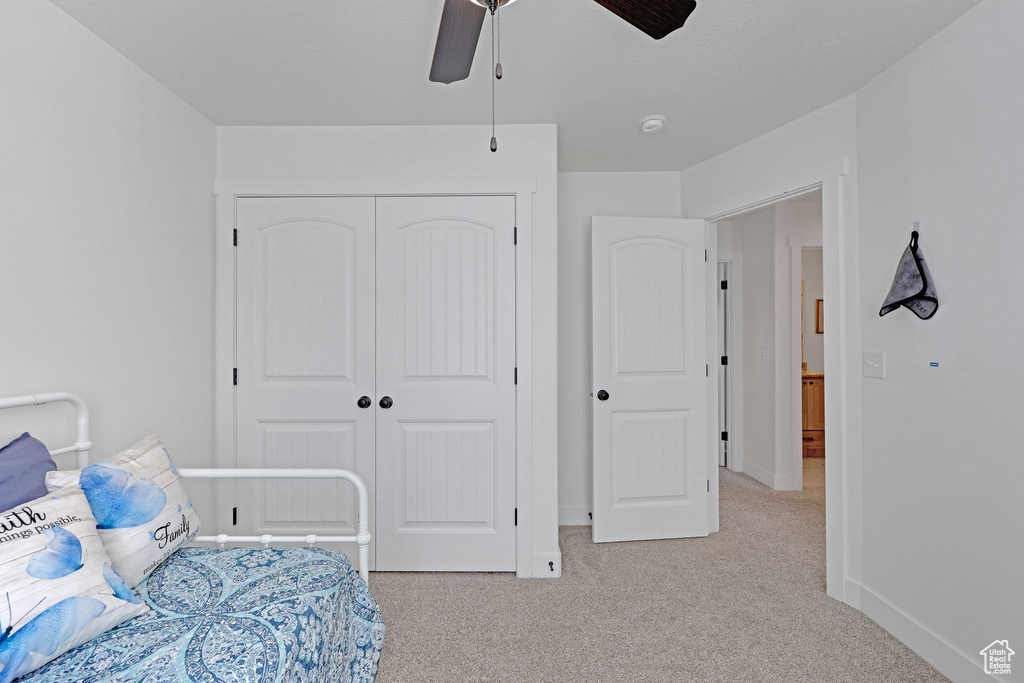 Bedroom featuring light carpet, a closet, baseboards, and ceiling fan
