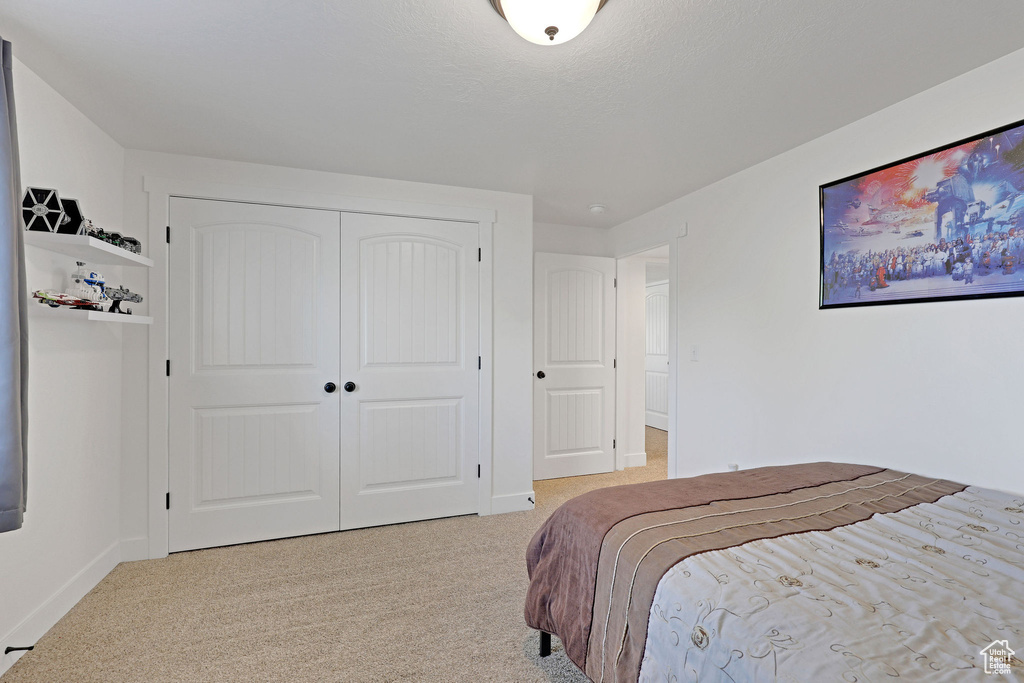 Carpeted bedroom with a closet and baseboards