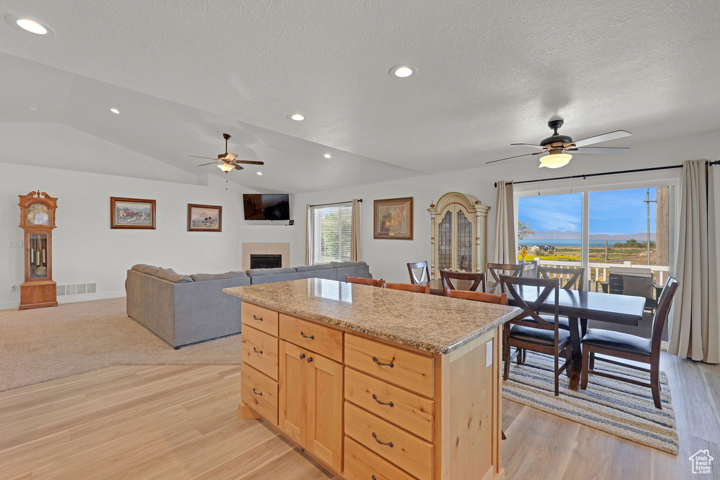 Kitchen with a ceiling fan, light wood-style floors, light brown cabinets, a fireplace, and a textured ceiling