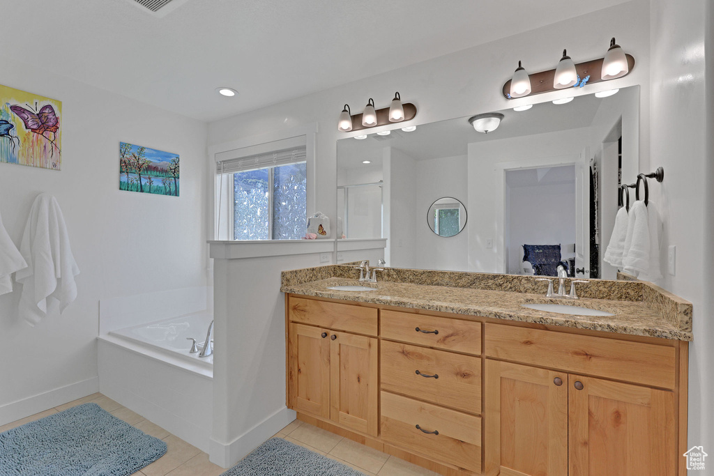 Bathroom featuring tile patterned floors, double vanity, a bath, a shower stall, and baseboards