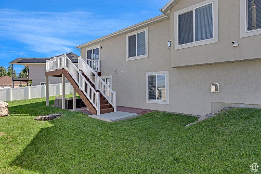 Rear view of property featuring a deck, stairway, and stucco siding