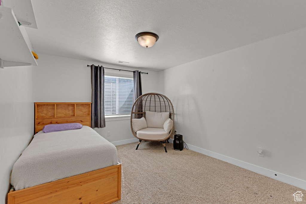 Bedroom with light colored carpet, baseboards, and a textured ceiling