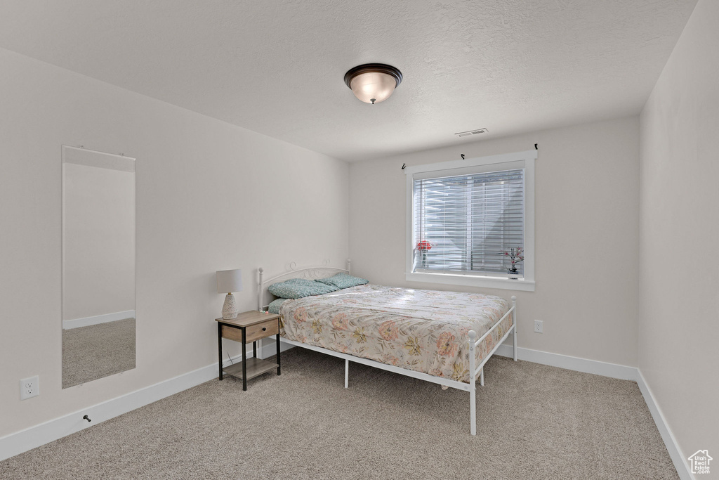 Bedroom with carpet floors, baseboards, and a textured ceiling