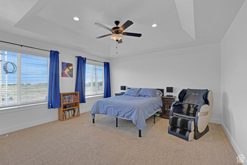Carpeted bedroom with a raised ceiling, baseboards, recessed lighting, and ceiling fan