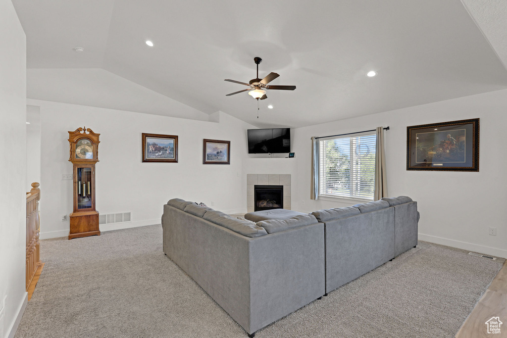 Living room with lofted ceiling, ceiling fan, a tile fireplace, baseboards, and recessed lighting