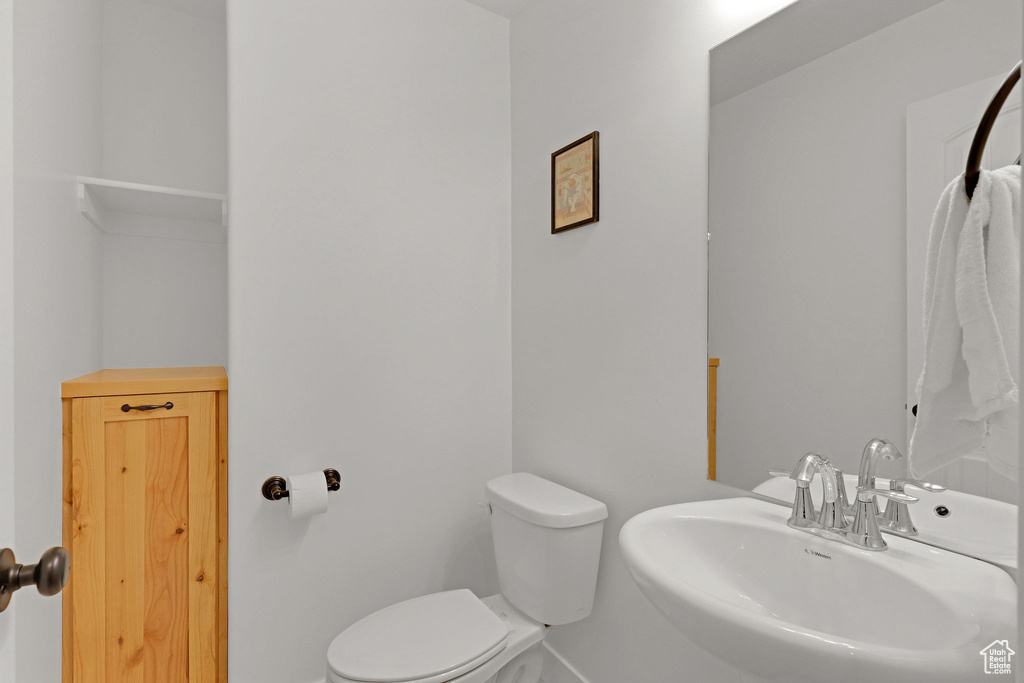 Bathroom featuring a sink, toilet, and baseboards