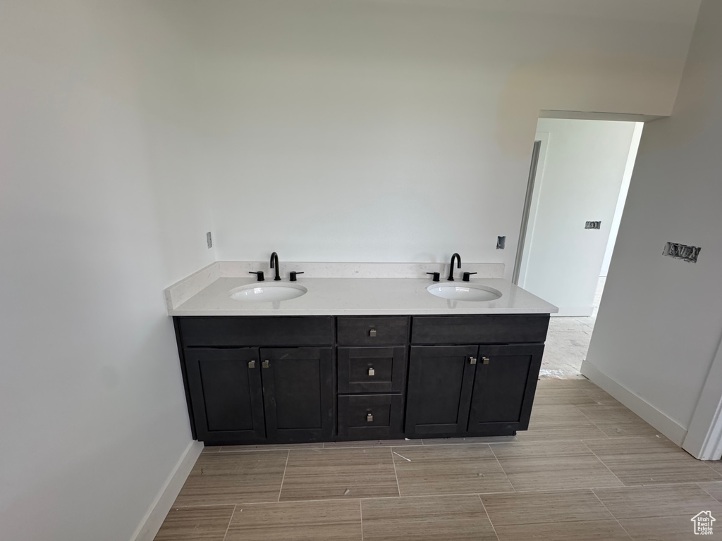 Full bath featuring double vanity and wood finish floors