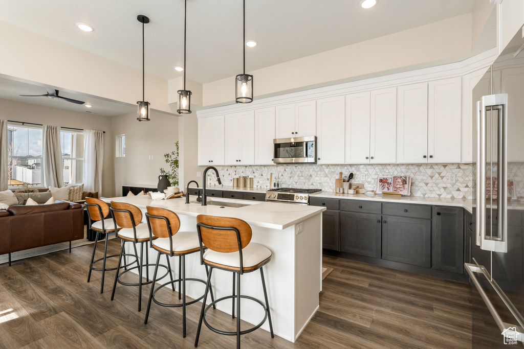 Kitchen with stainless steel appliances, open floor plan, a sink, white cabinets, and recessed lighting