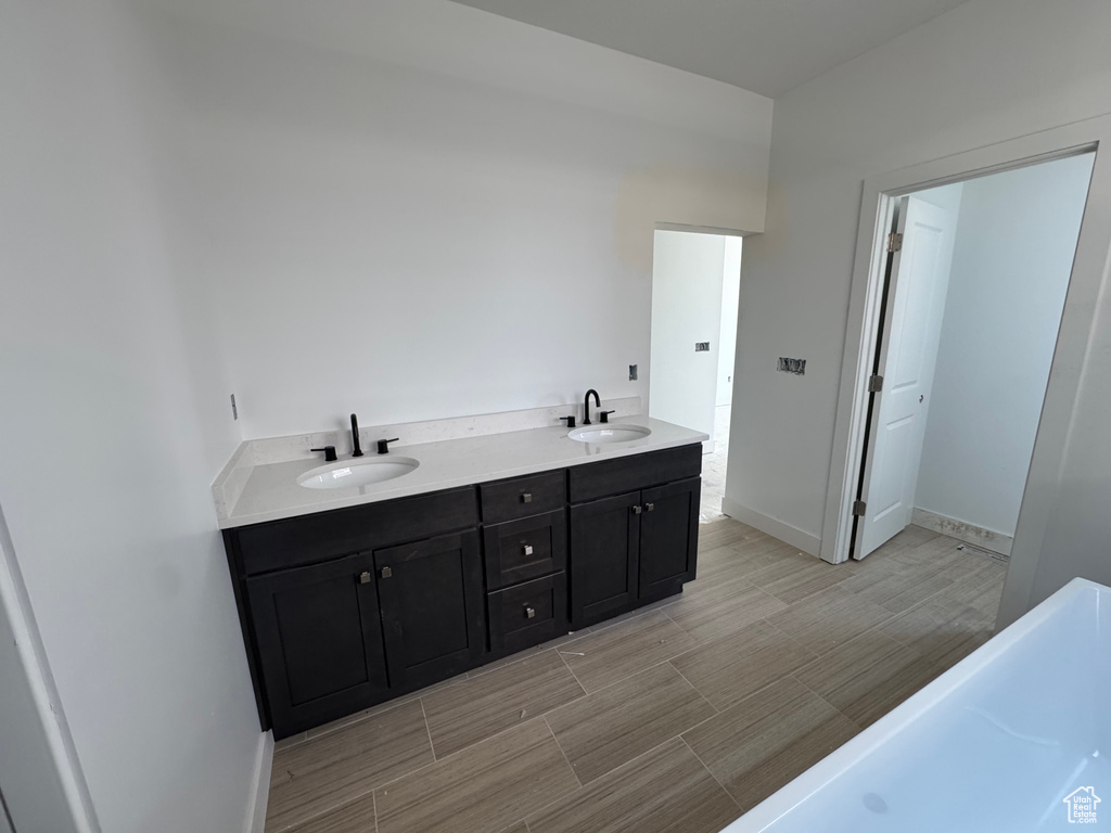 Bathroom featuring double vanity, wood tiled floors, and a tub