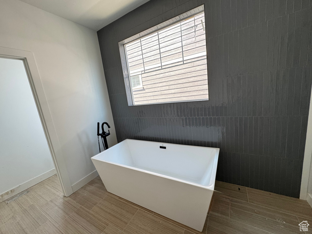 Full bathroom with a soaking tub and baseboards