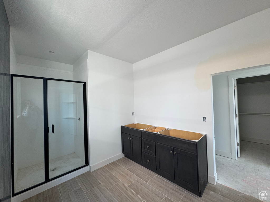 Full bath featuring a stall shower, baseboards, a textured ceiling, and wood finish floors